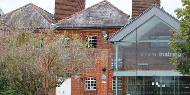 red brick building with glass front. trees on the left