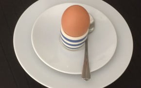 Egg in blue and white egg cup on white plate.