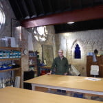 male in workshop, stone walls in background.