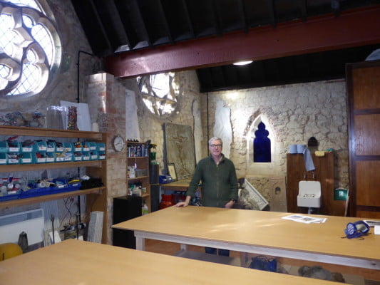 male in workshop, stone walls in background.