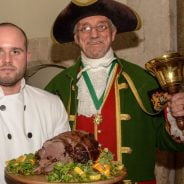 Piper, chef holding venison on a platter and the Town Crier.