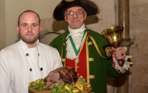 Piper, chef holding venison on a platter and the Town Crier.