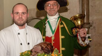 Piper, chef holding venison on a platter and the Town Crier.