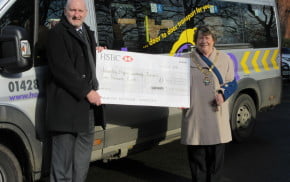 Man and Mayor stand to the side of a community bus holding large cheque