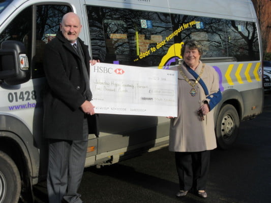 Man and Mayor stand to the side of a community bus holding large cheque