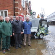 Six men in front of electric vehicle.