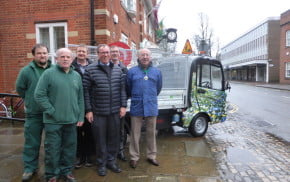 Six men in front of electric vehicle.