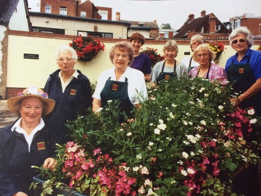 Group of females standing behind a display of plants