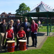 Four males and one female standing behind two children with drums