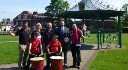 Four males and one female standing behind two children with drums