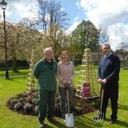 Two males and one female standing in front of flower bed