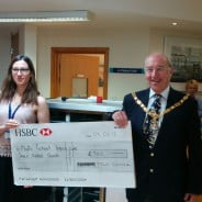 Two males and a female with holding a large cheque.