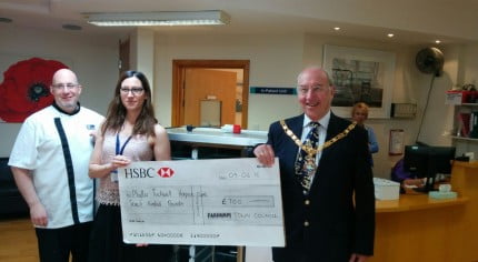 Two males and a female with holding a large cheque.