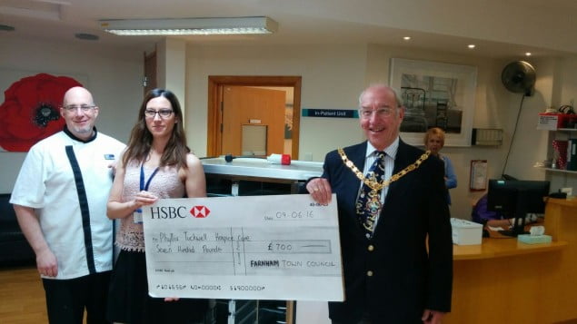 Two males and a female with holding a large cheque.