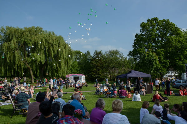 90 balloons released in park with groups of people watching