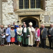 A group of people dressed in smart clothes and hats stood in front of a church.