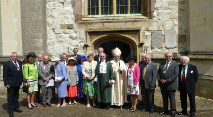 A group of people dressed in smart clothes and hats stood in front of a church.