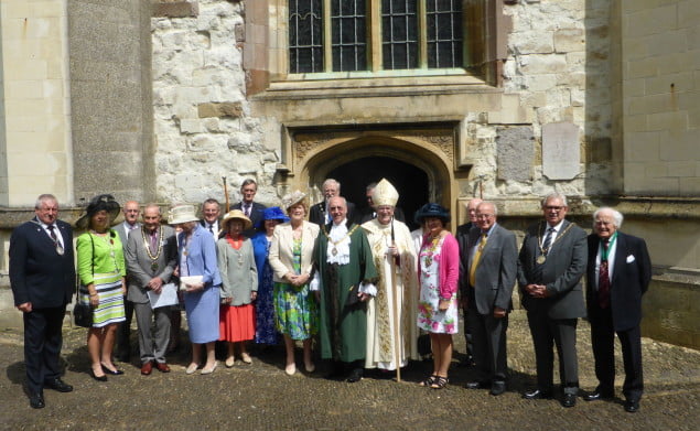 A group of people dressed in smart clothes and hats stood in front of a church.