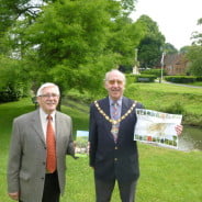 Two males holding a leaflet in a park.