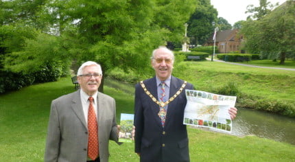 Two males holding a leaflet in a park.