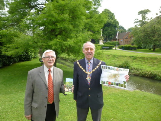 Two males holding a leaflet in a park.