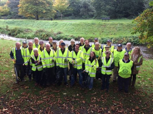 Group of people in high viz jackets with litter pickers and black sacks.