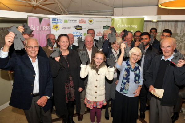 Group of people holding up grey gloves.