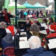 Orchestra playing in a bandstand and wearing Christmas hats.