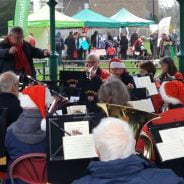 Orchestra playing in a bandstand and wearing Christmas hats.