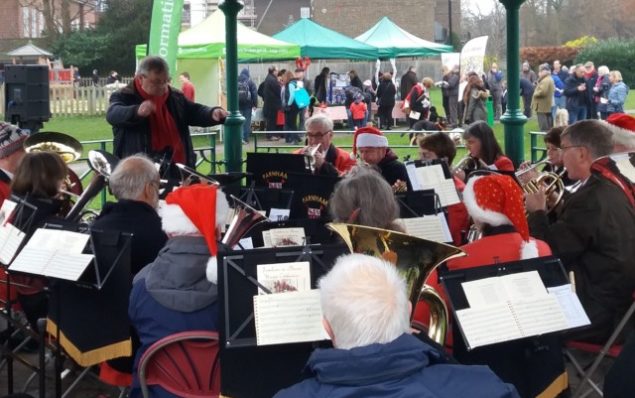 Orchestra playing in a bandstand and wearing Christmas hats.