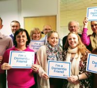 Group of people holding up signs saying "I'm a dementia friend."