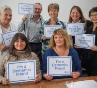 Group of people holding up signs saying "I'm a dementia friend."