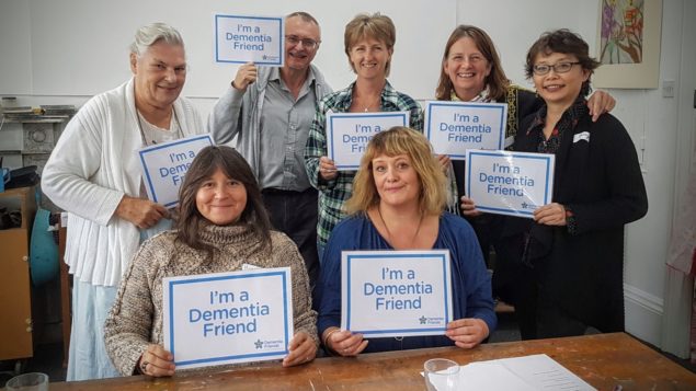 Group of people holding up signs saying "I'm a dementia friend."