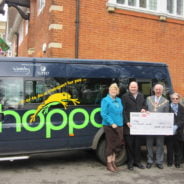 People in front of bus receiving a cheque.