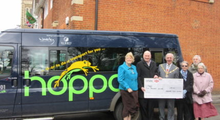 People in front of bus receiving a cheque.