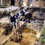 Excavation of a yard. Male with a wheelbarrow. Holes in ground.