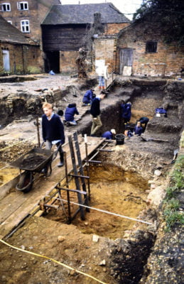 Excavation of a yard. Male with a wheelbarrow. Holes in ground.