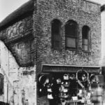 Black and white photo of a shop with baskets handing outside