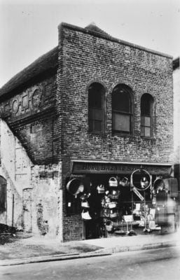 Black and white photo of a shop with baskets handing outside