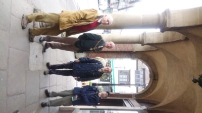 Four males standing under a stone arch.