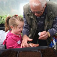 Male and child planting seeds at gardening workshop.