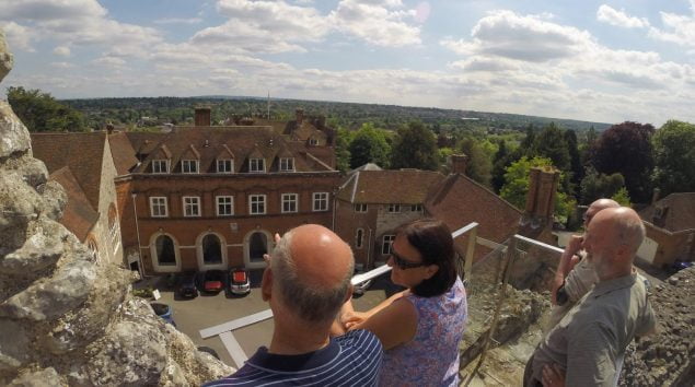 Group of people standing on viewing platform looking at Farnham Castle.
