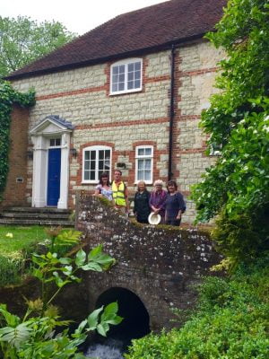 People on a stone bridge with a house behind.