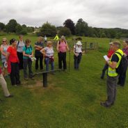 Group of walkers standing in field listening to walk guide.