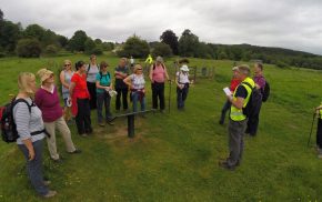 Group of walkers standing in field listening to walk guide.