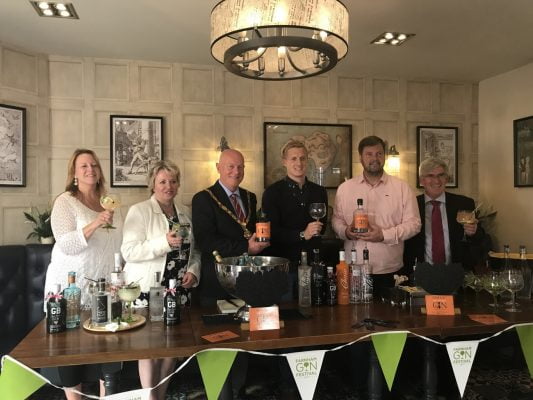 Mayor and group of people holding gin glasses.