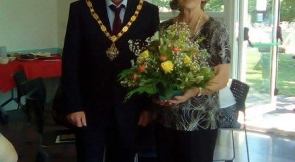 Mayor presenting female with a bouquet of flowers.