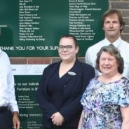 Group of people in front of a green sign.