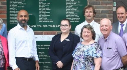 Group of people in front of a green sign.