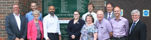 Group of people in front of a green sign.